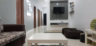a living room with a couch and a tv on a wall at Fahaz Lumut Homestay in Lumut