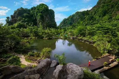a person standing on a bridge over a lake in a mountain at The Banjaran Hotsprings Retreat in Ipoh