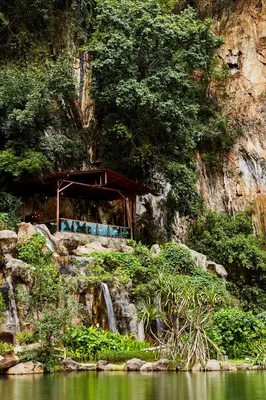a building on the side of a mountain with a waterfall at The Banjaran Hotsprings Retreat in Ipoh