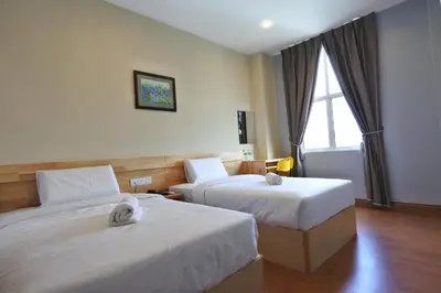 a hotel room with two beds and a window at Hotel Dutaria in Ipoh