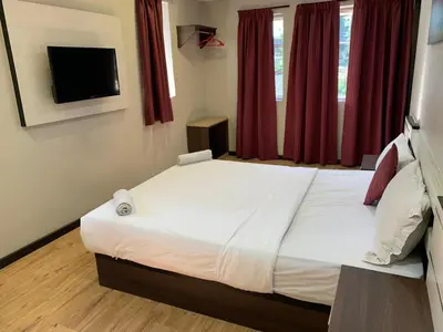 a bedroom with a large white bed with red curtains at Zermatt Hotel in Cameron Highlands