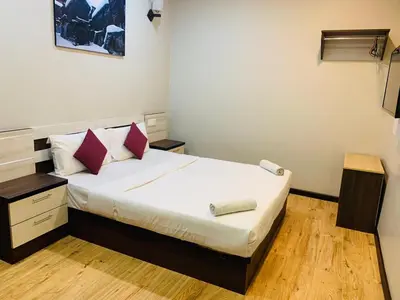 a small bedroom with a bed with white sheets and red pillows at Zermatt Hotel in Cameron Highlands