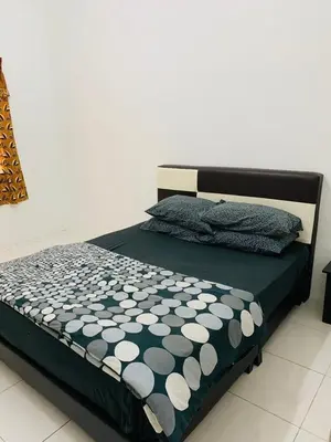 a bed with a black and white comforter on it at Zahara Homestay in Cameron Highlands