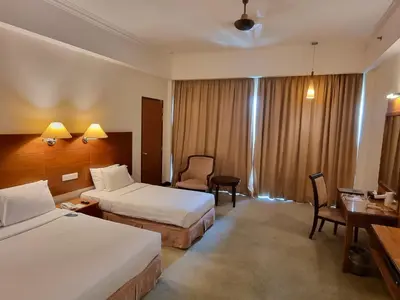 a hotel room with two beds and a desk at Heritage Hotel Cameron Highlands in Cameron Highlands