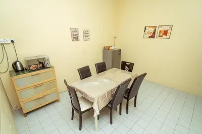 a dining room with a table and chairs and a refrigerator at GLYSM Tambun Stay in Ipoh