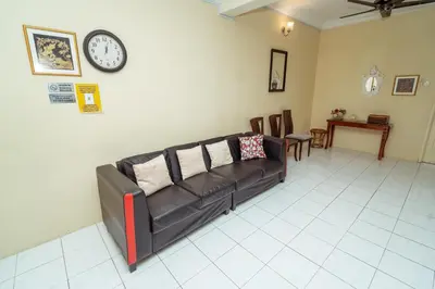 a living room with a couch and a clock on the wall at GLYSM Tambun Stay in Ipoh