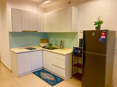 a small kitchen with white cabinets and a black refrigerator at Mansion One by Hejmo Suites in George Town