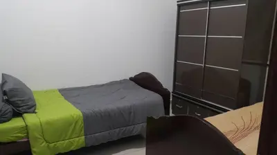 a bedroom with a bed and a dresser at Woon Homestay in Balik Pulau