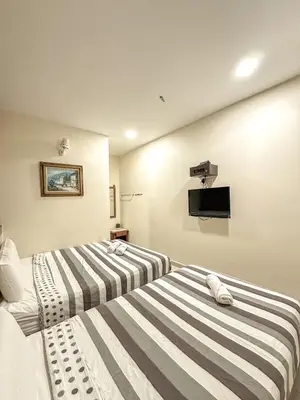 two beds in a room with a tv on the wall at G Star Hotel in Pantai Remis