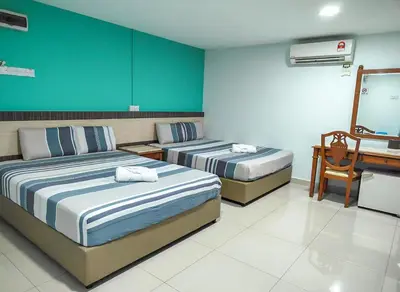 two beds in a hotel room with a desk at G Star Hotel in Pantai Remis