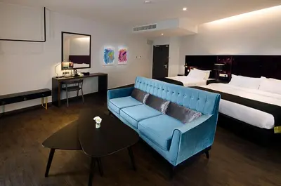 a hotel room with a blue couch and a bed at Palm Hotel Ipoh in Ipoh