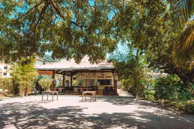 a building with chairs and tables under a tree at Pangkor Sandy Beach Resort in Pangkor