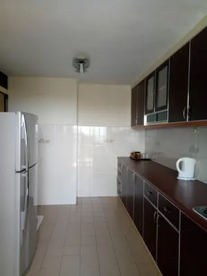 a kitchen with brown cabinets and a white refrigerator at Lumut Valley Resort Condominium in Lumut