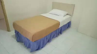 a small bed in a white room with blue skirt at Lumut Valley Resort Condominium in Lumut