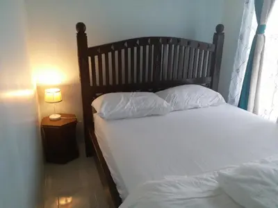 a bed with white sheets and pillows next to a window at VVIP Homestay Villa Proton City in Tanjung Malim