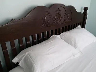 a bed with a wooden head board with white pillows at VVIP Homestay Villa Proton City in Tanjung Malim