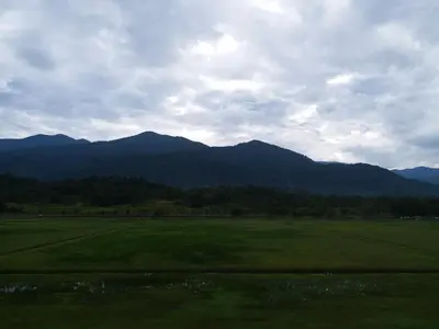 a green field with mountains in the background at VVIP Homestay Villa Proton City in Tanjung Malim