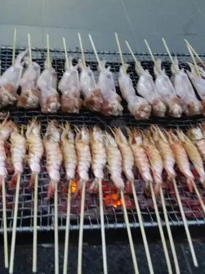 a row of chickens and chicken legs cooking on a grill at Pangkor Holiday Home in Pangkor