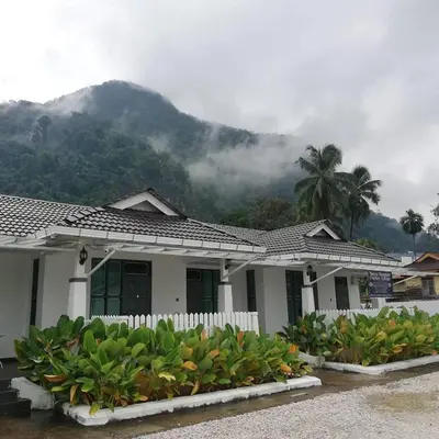 a white house with a mountain in the background at Baling Mountain Garden Village in Baling