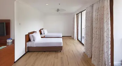 a white room with a bed and a window at The Bayview Beach Resort in Batu Ferringhi