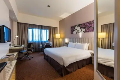 a hotel room with a bed and a person sitting in a chair at Sunway Hotel Seberang Jaya in Perai