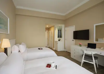 a hotel room with two beds and a desk at Berjaya Penang Hotel in George Town