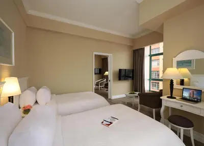a hotel room with a bed and a desk with a laptop at Berjaya Penang Hotel in George Town