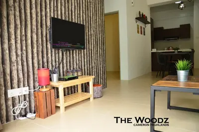 a living room with a television on a wall with a table at The Woodz Homestay - 3 Bedroom in Cameron Highlands