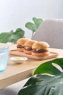 two hamburgers on a cutting board on a table at M Social Resort Penang in George Town