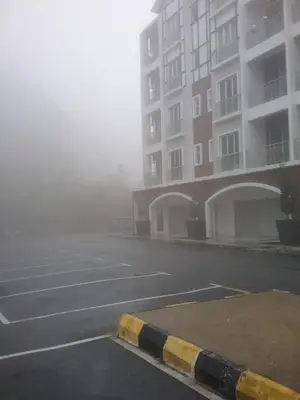 a foggy street with a parking lot and a building at NAZMI & LINDA CAMERON HOMESTAY in Cameron Highlands