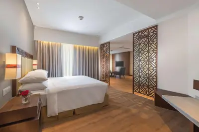 a bedroom with a white bed and a desk and a room at DoubleTree Resort by Hilton Hotel Penang in Batu Ferringhi