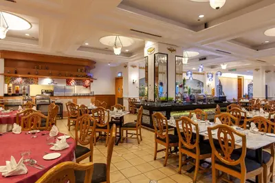a restaurant with tables and chairs and a kitchen at Bayview Hotel Georgetown Penang in George Town