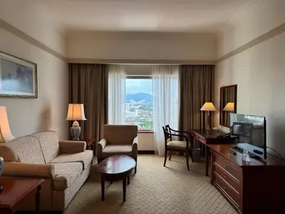 a hotel room with a couch and a desk and a television at Gurney Bay Hotel, A PARKROYAL Partner Hotel in George Town