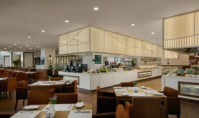 a restaurant with tables and chairs and a kitchen at Gurney Bay Hotel, A PARKROYAL Partner Hotel in George Town
