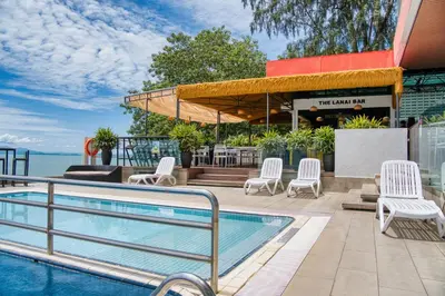 a swimming pool with white chairs next to a building at Hotel Sentral Seaview @ ​Beachfront in George Town