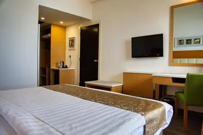 a hotel room with a bed and a desk and a television at Hotel Sentral Seaview @ ​Beachfront in George Town