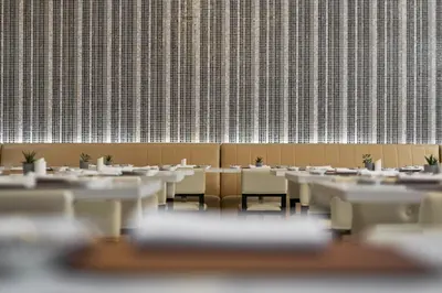 a row of tables and chairs in a room with a wall at AC Hotel by Marriott Penang in Bayan Lepas
