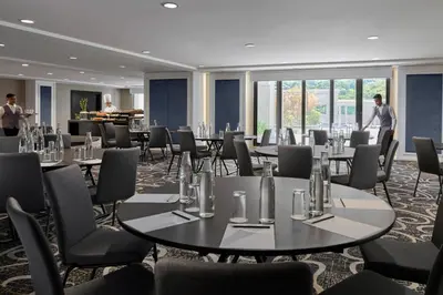 a room with tables and chairs and a man standing in the background at AC Hotel by Marriott Penang in Bayan Lepas