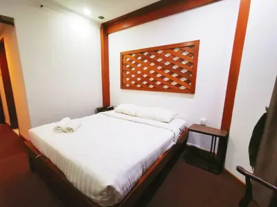 a bedroom with a white bed and a wooden headboard at Regalodge Hotel & Spa Ipoh in Ipoh