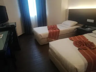 a hotel room with two beds and a television at Regalodge Hotel & Spa Ipoh in Ipoh
