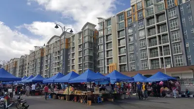 a market in front of a large building with blue umbrellas at My 2Rooms Apartments @ Golden Hills Pasar Malam in Cameron Highlands