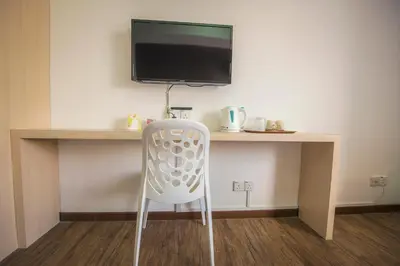 a white chair sitting in front of a desk with a television at YMCA Penang in George Town