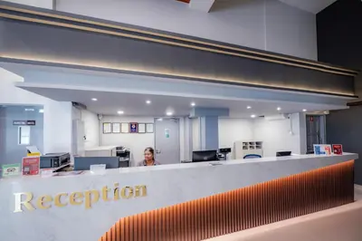 a woman standing behind a reception desk in an office at YMCA Penang in George Town