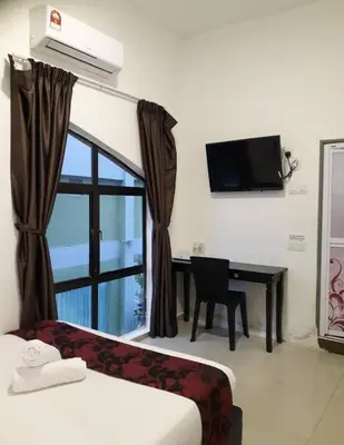a room with a bed and a desk and a window at Max Ferringhi Hotel in Batu Ferringhi