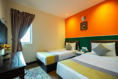 a hotel room with two beds and an orange wall at Link Hotel in George Town