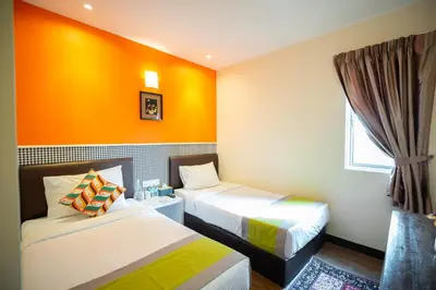 a room with two beds and an orange wall at Link Hotel in George Town