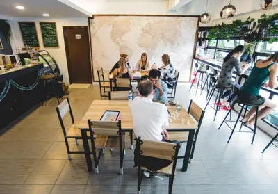 a group of people sitting at tables in a restaurant at Traveller Bunker Hostel in Cameron Highlands