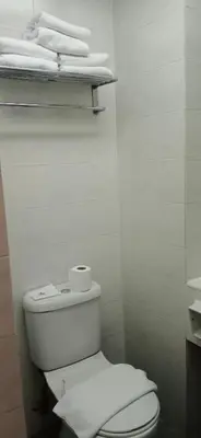 a white bathroom with a toilet and some towels at Hotel Seri Malaysia Ipoh in Ipoh