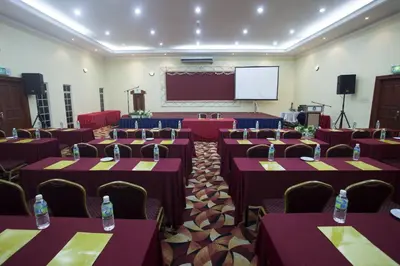 a conference room with tables and chairs and a screen at Hotel Seri Malaysia Ipoh in Ipoh