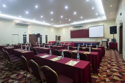 a conference room with tables and chairs and a screen at Hotel Seri Malaysia Ipoh in Ipoh